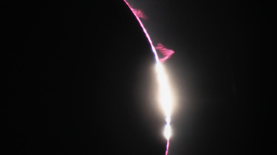 A photo of the eclipse with red plasma plumes around the sun's edge