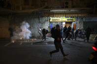 Palestinians run away as a stun grenades are fired by Israeli police during clashes at Damascus Gate just outside Jerusalem's Old City, Thursday, April. 22, 2021. Palestinians clashed with Israeli police over restrictions on Ramadan gatherings ahead of a planned march by Lahava, a Jewish extremist group, to the area later on Thursday amid heightened tensions in the city. (AP Photo/Mahmoud Illean)