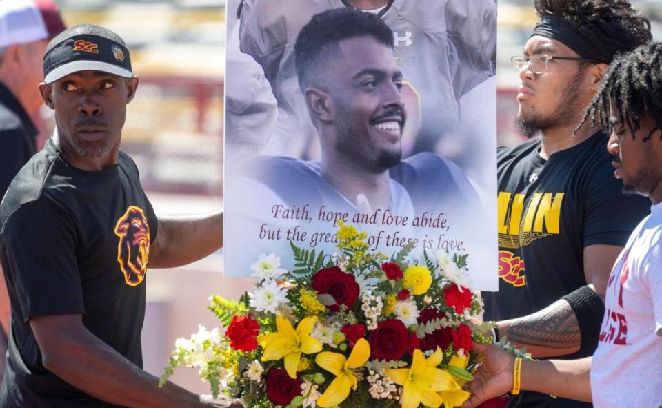 Sacramento City College head football coach Dannie Walker, left, brings a photo and flowers to the field before the start of their game Saturday, Sept. 16, 2023, in honor of 19-year-old offensive tackle Justin McAllister who died on Sept. 11 during practice.