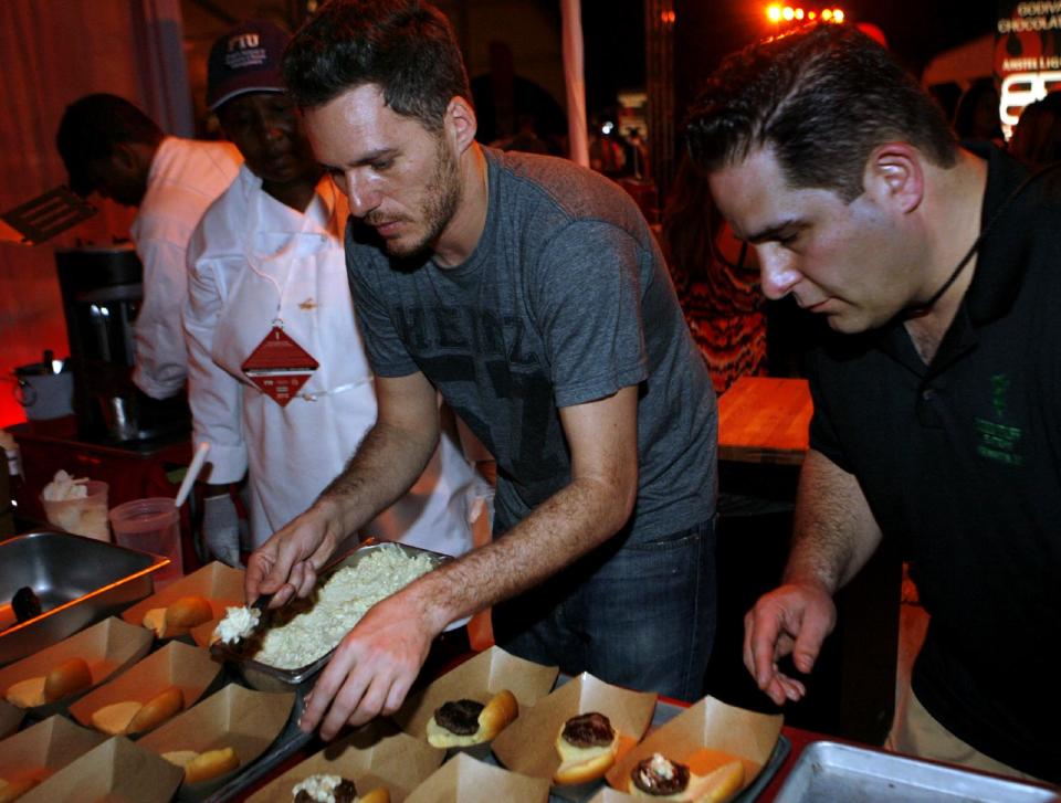 Spike Mendelsohn of Good Stuff Eatery, center, works on his creation while competing in the Burger Bash at the Food Network South Beach Wine & Food Festival in Miami Beach, Fla., Friday, Feb. 24, 2012. (AP photo/Jeffrey M. Boan)