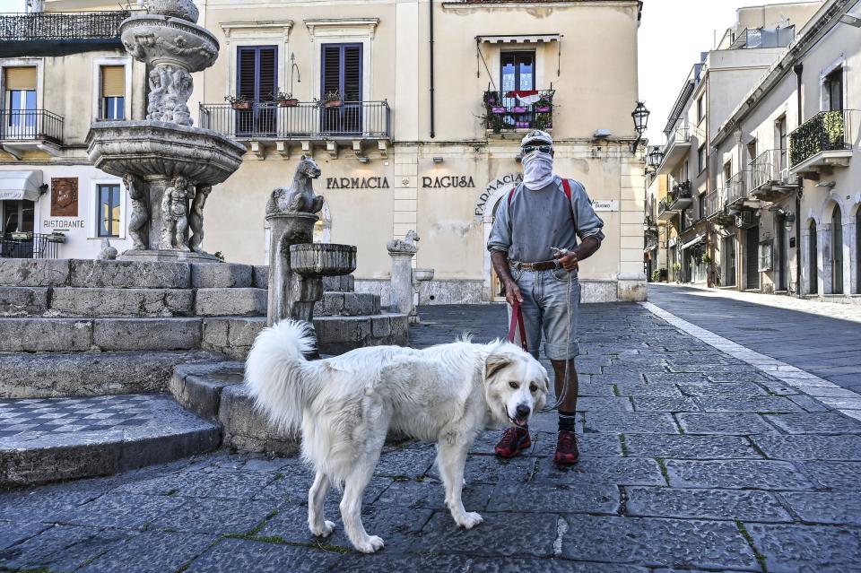 TAORMINA , ITALY - APRIL 08: A man wearing a protective mask walks his dog on April 08, 2020 in Taormina, Italy. There have been well over 100,000 reported COVID-19 cases in Italy and more than 15,000 related deaths, but the officials are confident the peak of new cases has passed. (Photo by Fabrizio Villa/Getty Images)