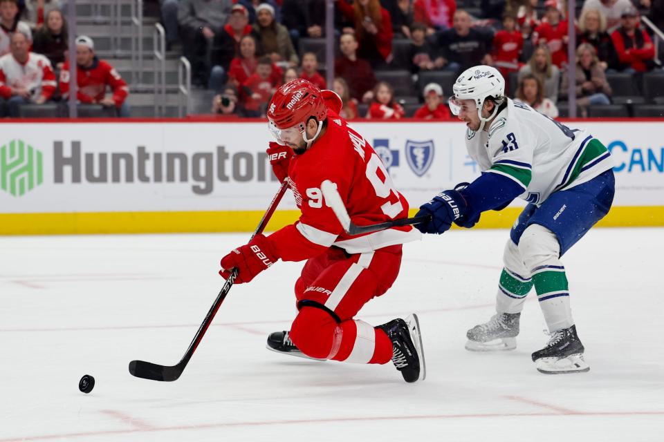 Detroit Red Wings defenseman Jake Walman (96) is hooked by Vancouver Canucks defenseman Quinn Hughes (43) in overtime at Little Caesars Arena in Detroit on Saturday, Feb. 10, 2024.
