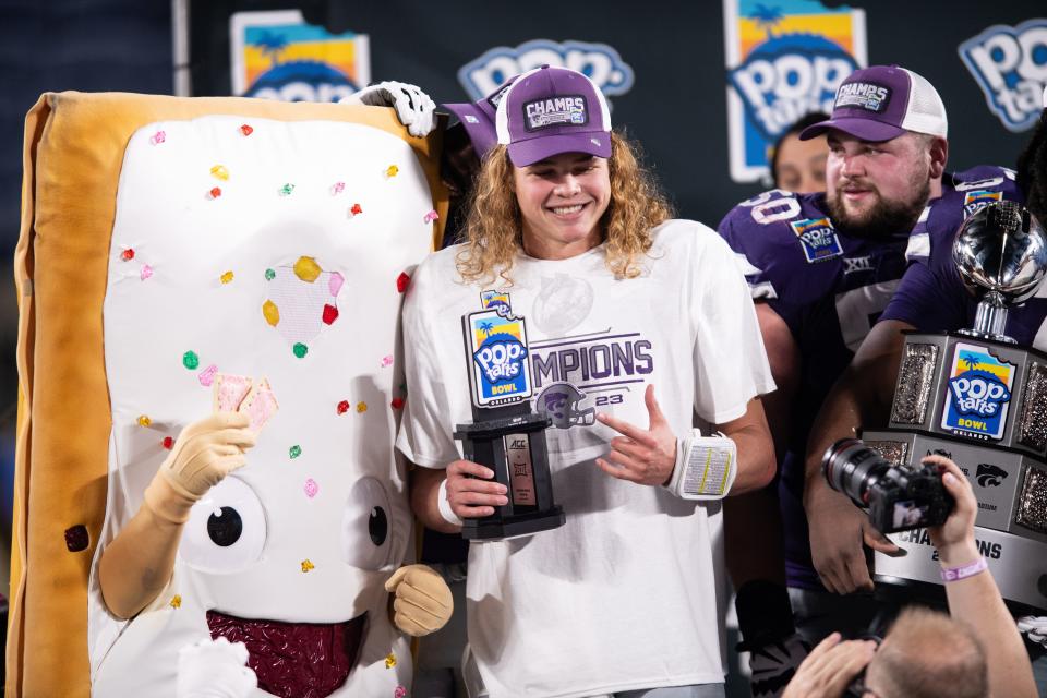 Kansas State quarterback Avery Johnson (2) celebrates his most valuable player honors with the Pop-Tarts Bowl mascot at Camping World Stadium in Orlando, Fla.