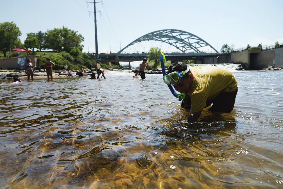 People cool off in the water at the confluence of the South Platte River and Cherry Creek in Denver, Monday, June 14, 2021. By mid-afternoon, the temperature hit 96 degrees as part of the heat wave sweeping across the western U.S. (AP Photo/Brittany Peterson)