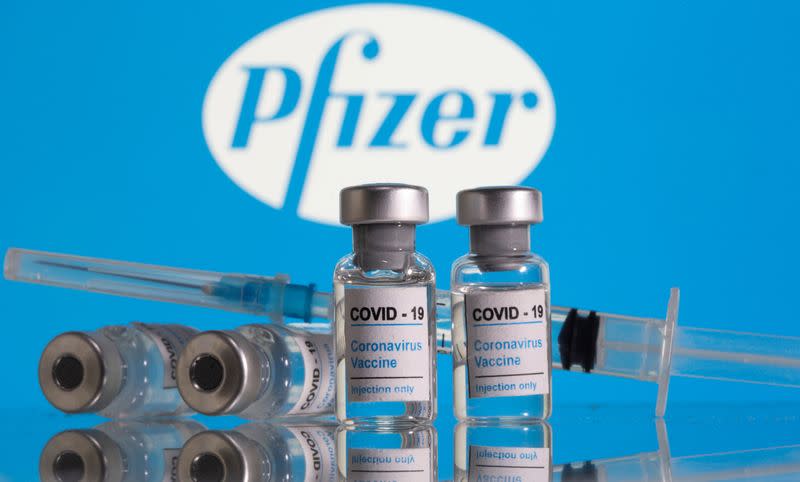 FILE PHOTO: Vials labelled "COVID-19 Coronavirus Vaccine" and sryinge are seen in front of displayed Pfizer logo in this illustration