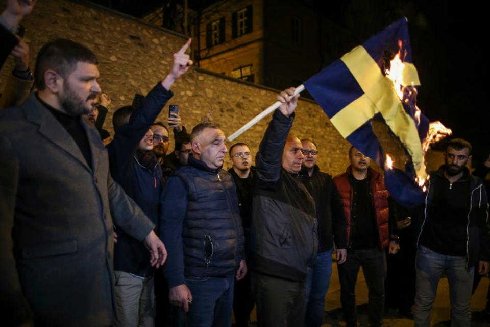 People set fire to a Sweden flag during a protest outside the Swedish consulate in Istanbul (AP)