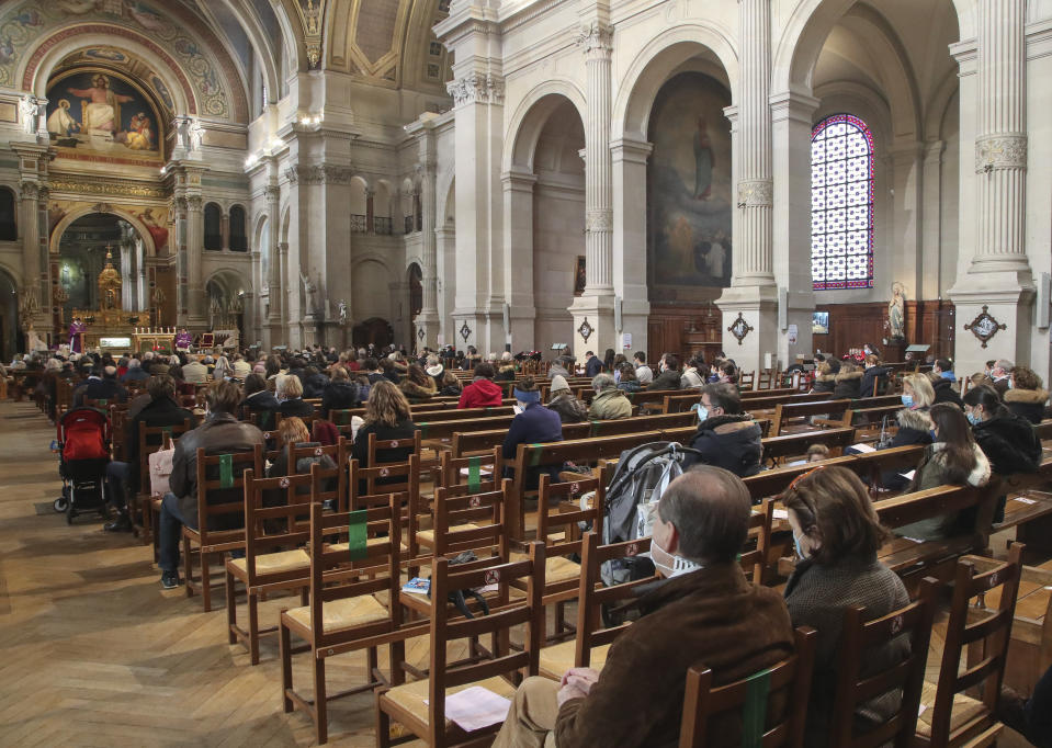 Church-goers wearing face masks as a precaution against the coronavirus attend a church service at Saint-Francois-Xavier church in Paris, Sunday, Nov. 29, 2020. French churches, mosques and synagogues can open their doors again to worshippers - but only a few of them, as France cautiously starts reopening after a second virus lockdown. Some churches may defy the 30-person limit they feel as too unreasonable, and other sites may stay closed until they can reopen for real. (AP Photo/Michel Euler)