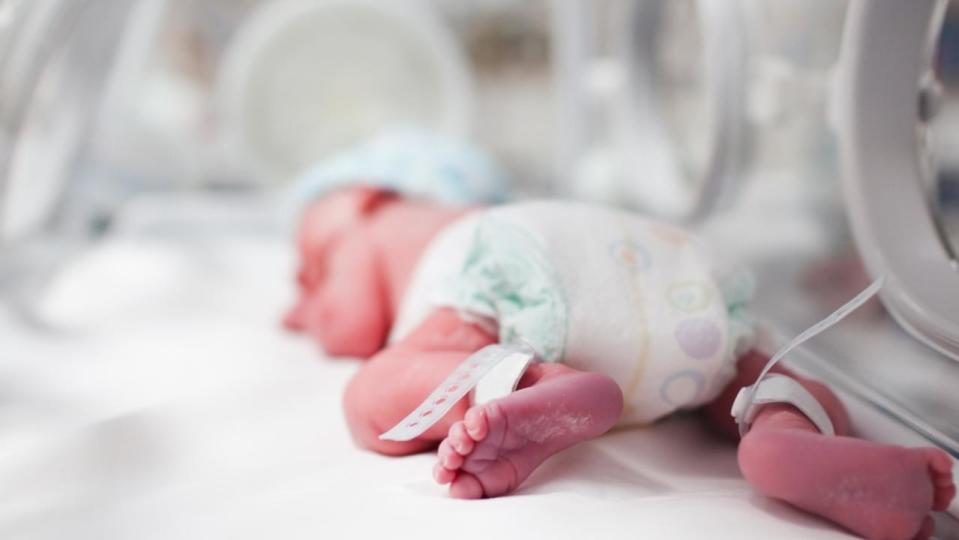 Newborn baby boy covered in vertix inside incubator