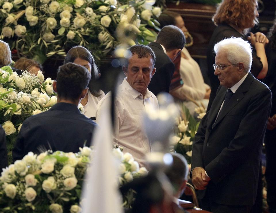 Italian President Sergio Mattarella, right, meets relatives attending a funeral service for some of the victims of a collapsed highway bridge, in Genoa's exhibition center Fiera di Genova, Italy, Saturday, Aug. 18, 2018. Saturday has been declared a national day of mourning in Italy and includes a state funeral at the industrial port city's fair grounds for those who plunged to their deaths as the 45-meter (150-foot) tall Morandi Bridge gave way Tuesday. (AP Photo/Gregorio Borgia)