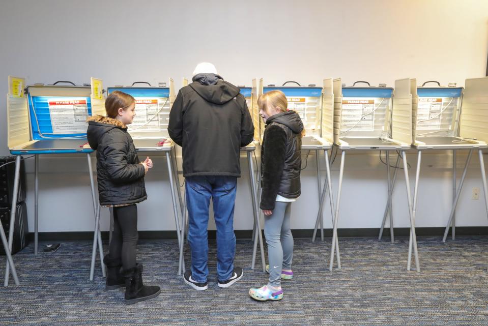 Ronald Gizzo fills out his ballot under the watchful eyes of his granddaughters Penny Damron, 10, left, and Violet Damron, 8, at the Nordonia Hills City Branch Library polling station Tuesday in Northfield.