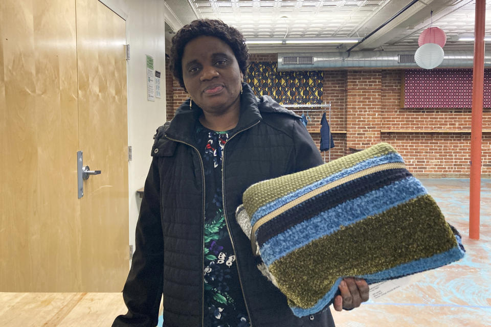 Sifania Assuma, who is originally from Congo, shows the handmade blanket she picked out at the blanket giveaway for refugees and immigrants on March 21, 2023, in Burlington, Vt. More than 80 blankets were made by Vermont and out-of-state crafters as gifts for refugees as part on the national Welcome Blanket project. Each included a personal note from the crafter about her or his own family history of immigration or migration. (AP Photo/Lisa Rathke)