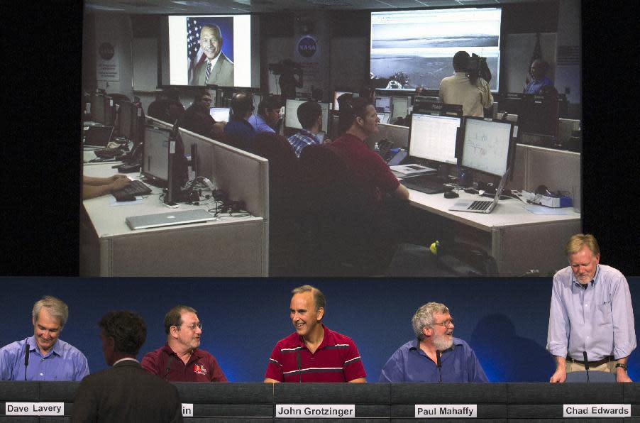 NASA scientists smile after NASA's Administrator Charles Bolden, seen on video projection on top left, debuted the first recorded human voice that traveled from Earth to another planet and back, as Bolden radioed the rover on Mars and back to NASA's Deep Space Network (DSN) on Earth, during a briefing at NASA's Jet Propulsion Laboratory in Pasadena, Calif., Monday, Aug. 27, 2012. From left: Mike Malin, imaging scientist for the Mars Science Laboratory, John Grotzinger, MSL project scientist, California Institute of Technology, Paul Mahaffy, NASA Goddard Space Flight Center, and Dr. Chad Edwards, Chief Telecommunications Engineer for the Mars Exploration Program at JPL. (AP Photo/Damian Dovarganes)