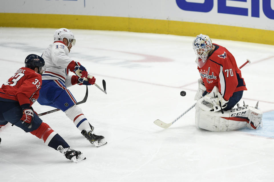 Washington Capitals goaltender Braden Holtby (70) stops the puck against Montreal Canadiens center Max Domi (13) during the first period of an NHL hockey game, Thursday, Feb. 20, 2020, in Washington. Also seen is Capitals defenseman Radko Gudas (33). (AP Photo/Nick Wass)