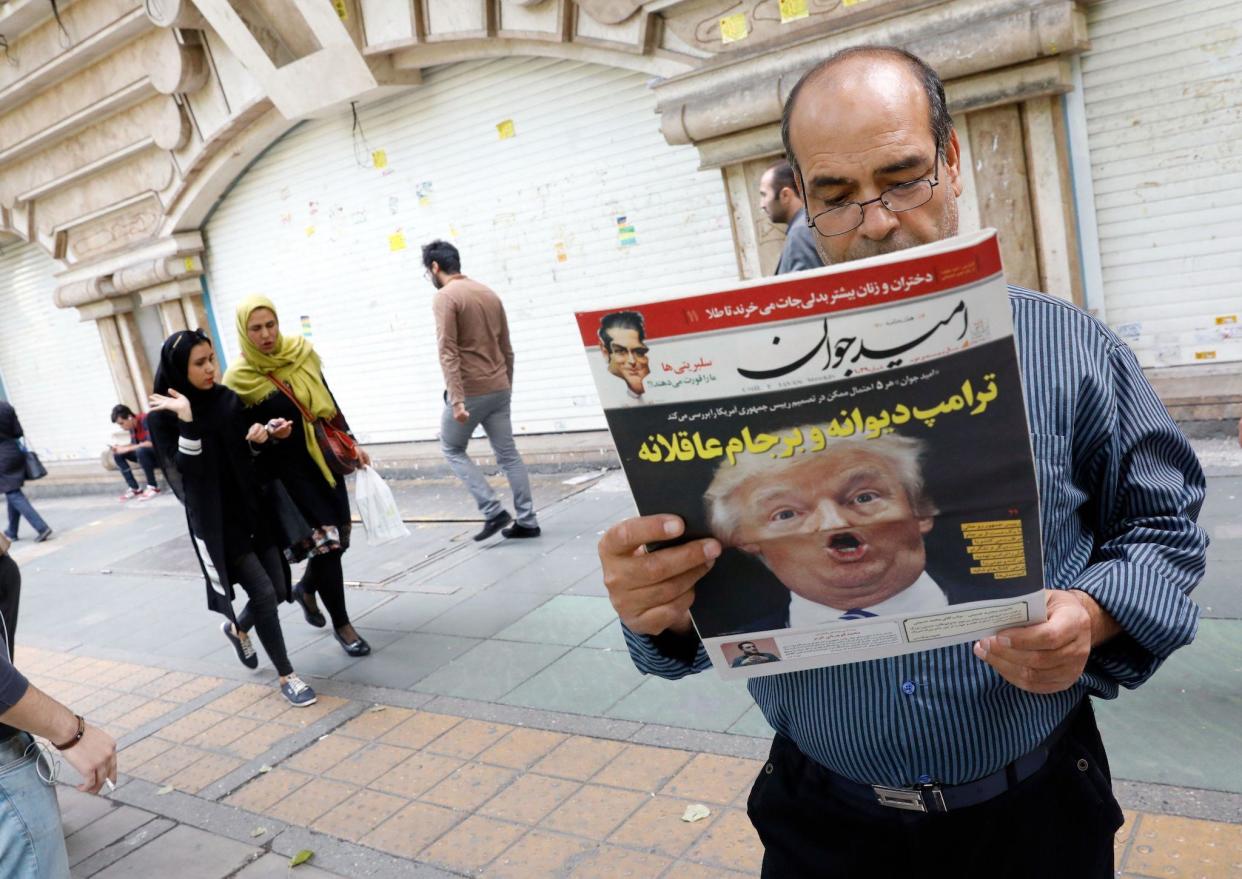 An Iranian man reads a copy of the daily newspaper 'Omid Javan' bearing a picture of US President Donald Trump with a headline that reads in Persian 'Crazy Trump': AFP/Getty Images