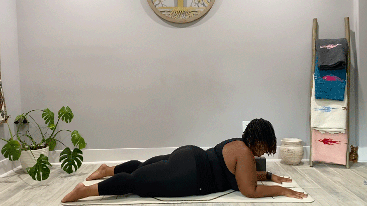 Woman lying on her belly on her yoga mat with her forearms down