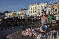 In this Sept. 7, 2019 photo, a fish vendor prepares fish for customers at her street stand at the Ver-o-Peso riverside market in Belém, Brazil. Ver-O-Peso at the Guajara Bay riverside was originally a tax collection center for goods from the Amazon paid to the Portuguese crown. (AP Photo/Rodrigo Abd)