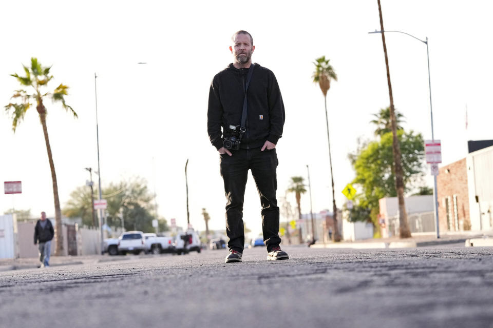 Documentary photographer Eric Elmore stands where homeless camp called "The Zone" used to encompass, Tuesday, Dec 19, 2023, in Phoenix. Elmore documented Phoenix's homeless people in addition to Roosevelt White III, who was 36 when he died of a stroke in September after falling ill in the Phoenix homeless encampment known as "The Zone". Roosevelt is among thousands of homeless people who died this year and are being remembered at winter solstice events for Homeless Persons' Memorial Day. (AP Photo/Matt York)