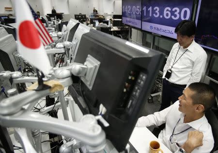 Employees of a foreign exchange trading company chat as they work in front of monitors displaying the exchange rates between the Japanese yen and the U.S. dollar (front) and the yen against the euro (back) in Tokyo November 4, 2014. REUTERS/Yuya Shino