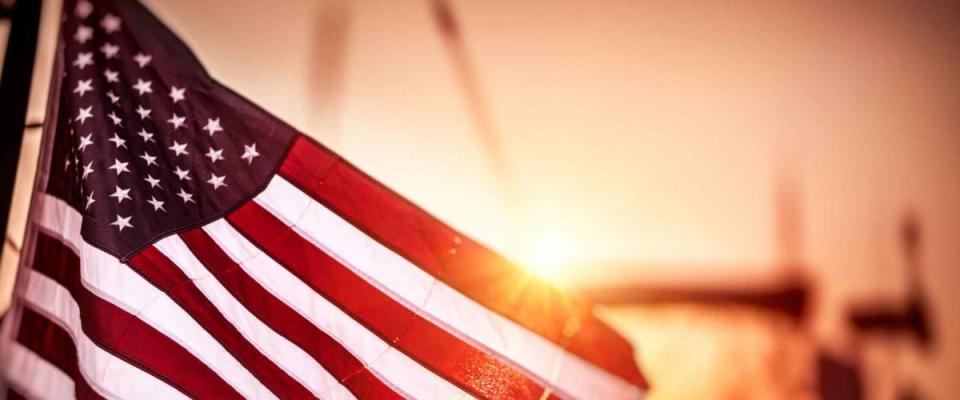 Flag of United States of America flutters in the winds in mild sunset light, independence day of America