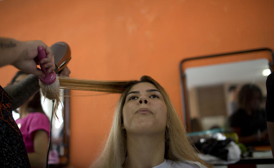 Una peluquera seca el pelo a una reclusa que se prepara para cometir en la 13ra edición del concurso de belleza Miss Talavera Bruce en la cárcel del mismo nombre, en Río de Janeiro, Brasil, el 4 de diciembre de 2018. Peluqueras y maquilladoras colaboran de forma voluntaria para preparar a las reclusas, que son juzgadas por su belleza, su atractivo y su actitud. (AP Foto/Silvia Izquierdo)