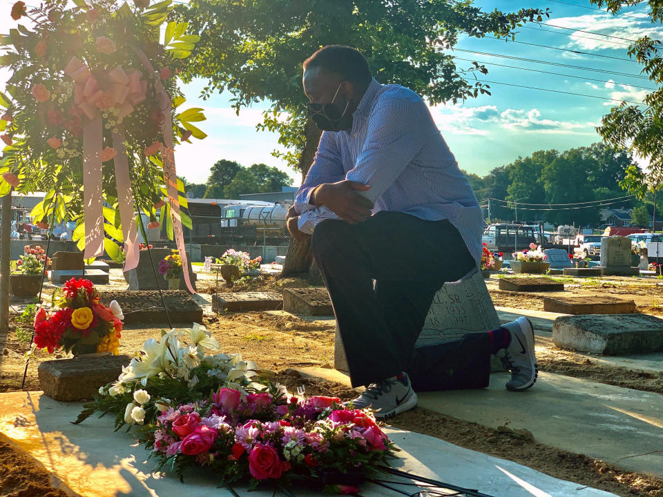 Will Boyd kneels at the grave of a family member who died after contracting the coronavirus, Saturday, June 20, 2020, in Montgomery, Ala. He says his family has lost multiple family members to COVID-19. (AP Photo/Kim Chandler)