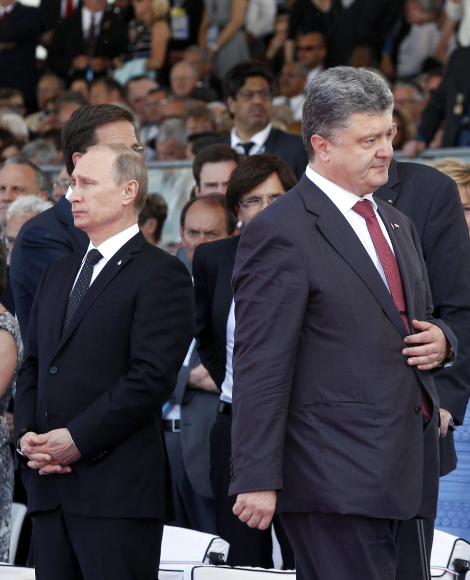 FILE - Ukrainian President Petro Poroshenko, right, walks past Russian President Vladimir Putin during the commemoration of the 70th anniversary of the D-Day in Ouistreham, western France, June 6, 2014. A peace agreement for eastern Ukraine has remained stalled for years, but it has come into the spotlight again amid a Russian military buildup near Ukraine that has fueled invasion fears. On Thursday, Feb. 10, 2022 presidential advisers from Russia, Ukraine, France and Germany are set to meet in Berlin to discuss ways of implementing the deal that was signed in the Belarusian capital of Minsk in 2015. (AP Photo/Christophe Ena, file)