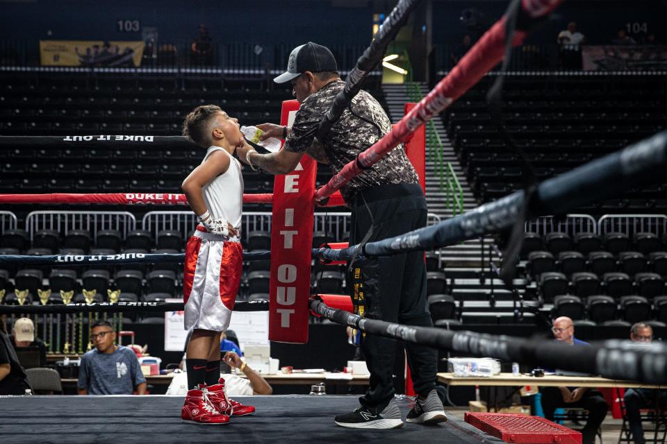 Duke It Out Coach Andres Luis gives Adrian Briseno IV, 11, water after winning his bout at the STABA Junior Olympic boxing tournament in the American Bank Center in Corpus Christi, Texas, Friday, June 10, 2022.