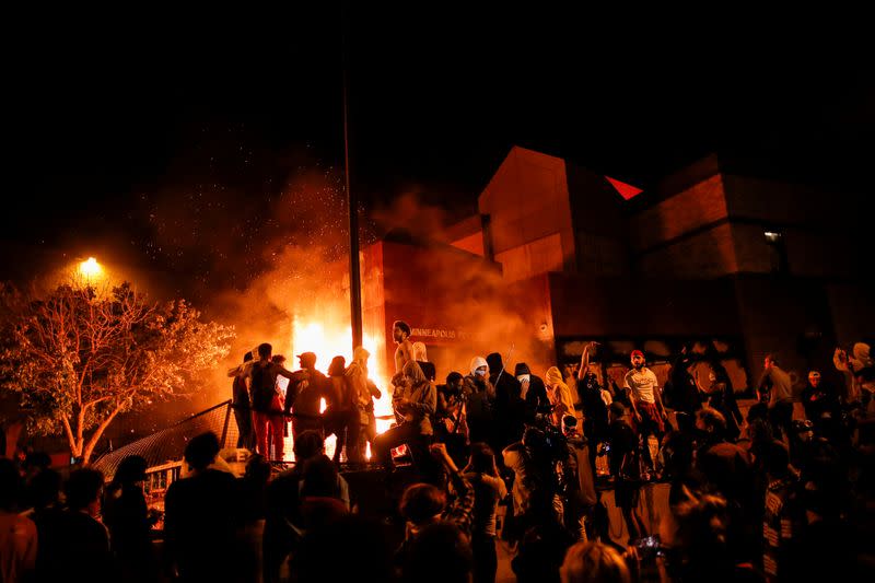 Protesters gather around after setting fire to the entrance of a police station as demonstrations continue in Minneapolis