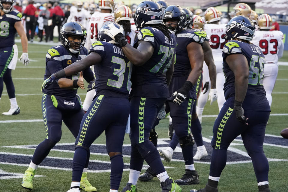 Seattle Seahawks quarterback Russell Wilson, left, greets running back DeeJay Dallas (31), second from left, after Dallas scored a touchdown against the San Francisco 49ers during the second half of an NFL football game, Sunday, Nov. 1, 2020, in Seattle. The Seahawks won 37-27. (AP Photo/Elaine Thompson)