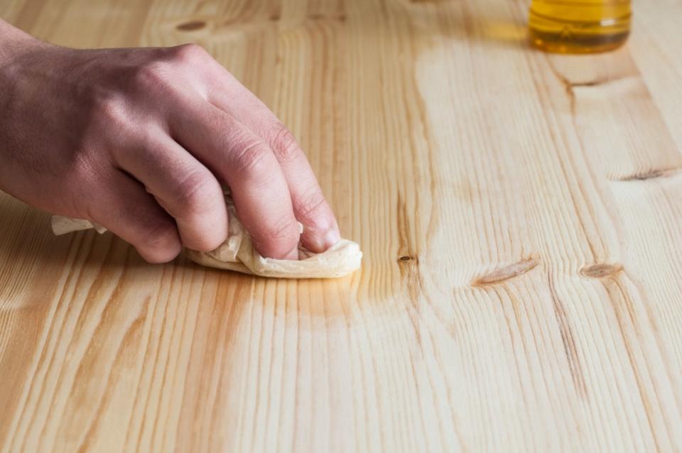 Person oiling a wood surface with a towel.