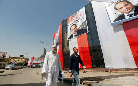 People walk in front of polling stations covered from outside by Egyptian flags and posters of Egypt's President Abdel Fattah al-Sisi during the preparations for tomorrow's presidential election in Cairo, Egypt, March 25, 2018. REUTERS/Amr Abdallah Dalsh