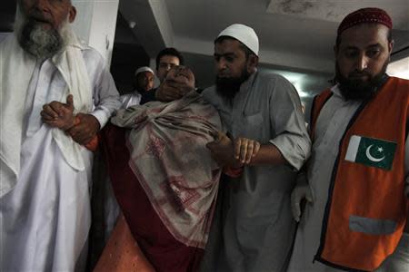 Men comfort a woman as she cries over the death of her son, who was killed in a bomb blast, at a hospital in Peshawar September 27, 2013. REUTERS Fayaz Aziz
