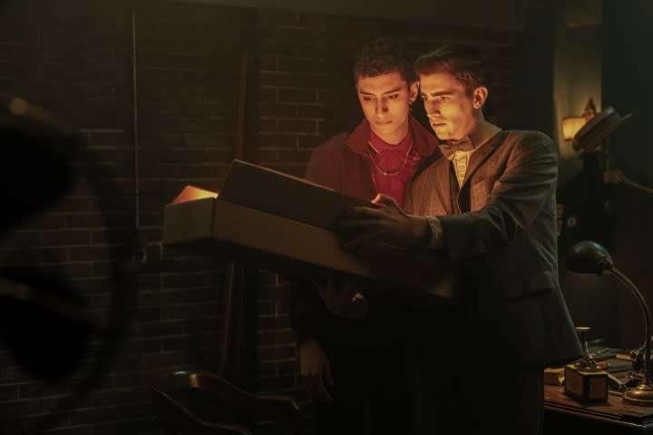 Two teen males read a glowing book in Dead Boy Detectives.