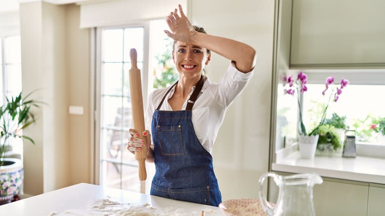 Frazzled-looking woman baking in kitchen 