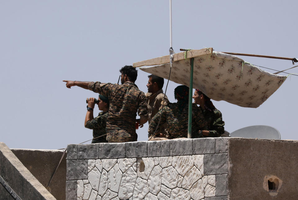 SDF fighters stand atop of a building near Raqqa city