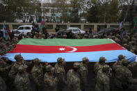 Azerbaijani soldiers carry a huge national flag as they celebrate the transfer of the Lachin region to Azerbaijan's control, as part of a peace deal that required Armenian forces to cede the Azerbaijani territories they held outside Nagorno-Karabakh, in Aghjabadi, Azerbaijan, Tuesday, Dec. 1, 2020. Azerbaijan has completed the return of territory ceded by Armenia under a Russia-brokered peace deal that ended six weeks of fierce fighting over Nagorno-Karabakh. Azerbaijani President Ilham Aliyev hailed the restoration of control over the Lachin region and other territories as a historic achievement. (AP Photo/Emrah Gurel)