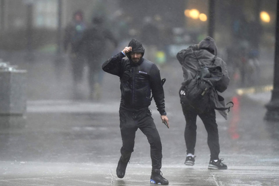 Pedestrians are buffeted by wind and rain as they cross a street, Monday, Dec. 18, 2023, in Boston. A storm moving up the East Coast brought heavy rain and high winds to the Northeast on Monday, threatening flooding, knocking out power to hundreds of thousands. (AP Photo/Steven Senne)