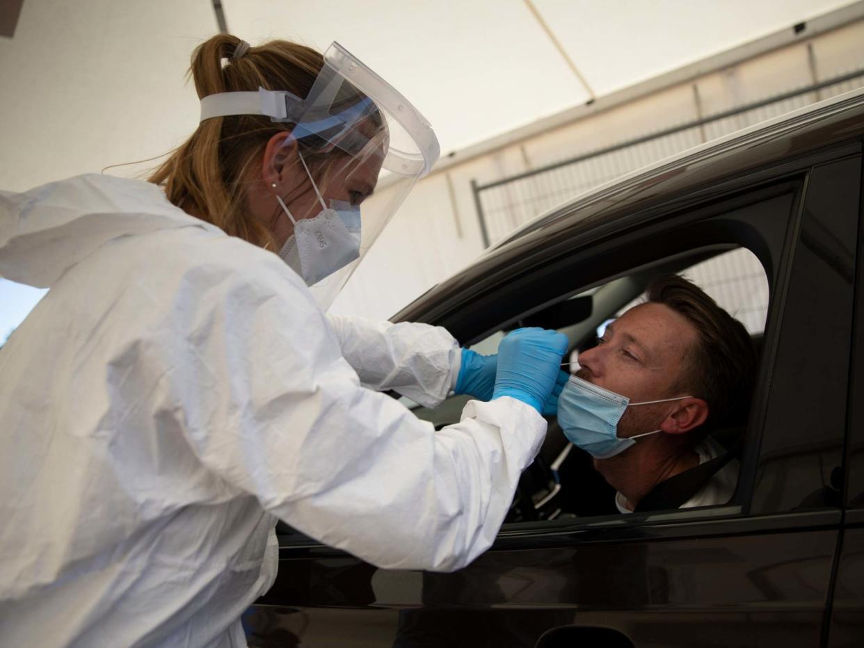 A healthcare worker demonstrates a nasal swab on a patient during a test day at a drive-through Covid-19 testing site: Virginia Mayo/AP