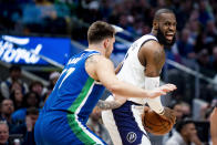 Los Angeles Lakers forward LeBron James instructs his teammates on the floor as Dallas Mavericks guard Luka Doncic defends him in the first half of an NBA basketball game in Dallas, Sunday, Dec. 25, 2022. (AP Photo/Emil T. Lippe)