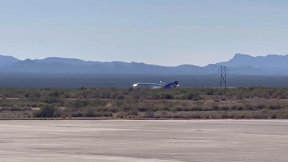 a silver space plane lands on a runway