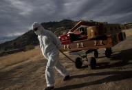 A funeral worker removes empty coffins that held remains that were later cremated, at La Recoleta cemetery in Santiago, Chile, Wednesday, April 21, 2021, amid the new coronavirus pandemic. (AP Photo/Esteban Felix)