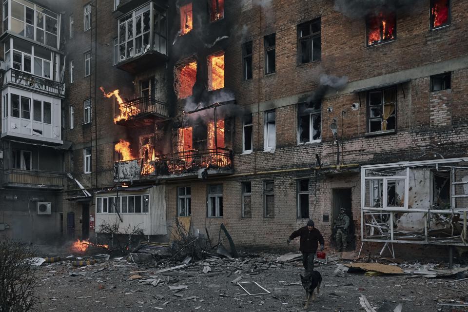 FILE - A local resident leaves his home after Russian shelling destroyed an apartment house in Bakhmut, Donetsk region, Ukraine, Wednesday, Dec. 7, 2022. Since October, Moscow has particularly focused on pummeling energy facilities and other key infrastructure with missile and drone strikes in an apparent hope of breaking the will of the Ukrainians and forcing Kyiv to negotiate on Russia's terms. (AP Photo/LIBKOS, File)