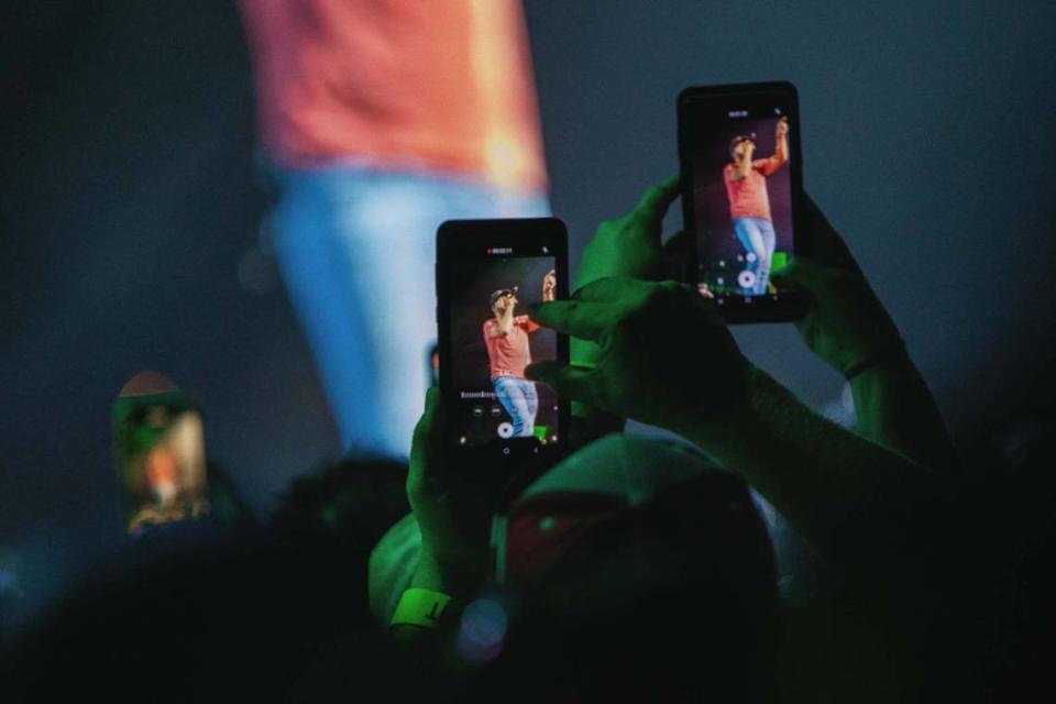 Fans capture moments from Friday night’s concert on their cellphones.