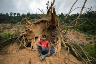 Elmer Ramirez, 22, sits for a portrait at the site of his home destroyed by a landslide triggered by hurricanes Eta and Iota in the village of La Reina, Honduras, Wednesday, June 23, 2021. "We made the decision for my wife to go to the United States because she was carrying the [five-month-old] baby and she could stay, but she had to make the whole trip nursing. Hopefully I can meet her in the near future in Miami. Our plan is to be able to build ourselves a house. Nobody leaves thinking of staying in the U.S. because our land is here." (AP Photo/Rodrigo Abd)