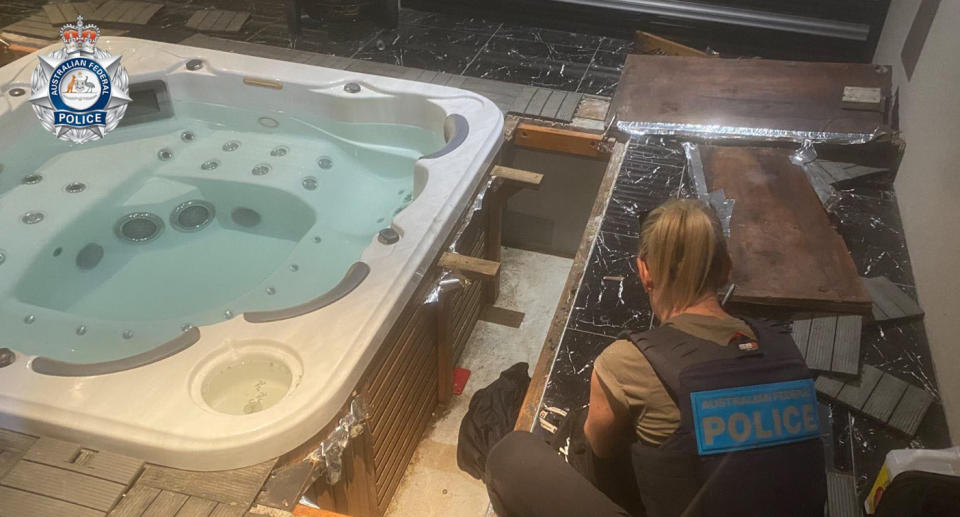 A female police officer crouched in front of the home spa with pieces of wood and tiles strewn over the floor beside her. 