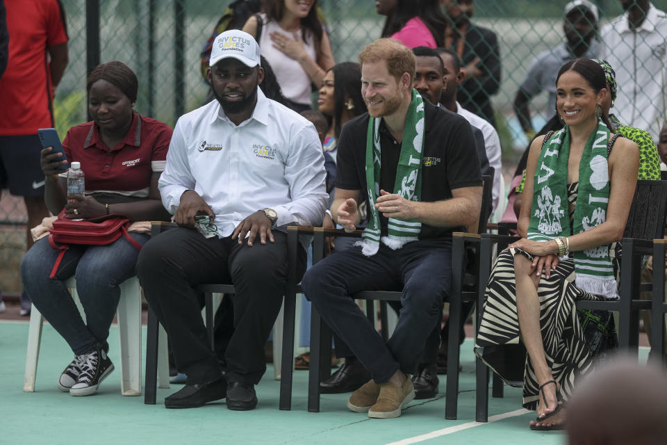 Meghan Markle sits with Prince Harry at a volleyball game wearing a palm frond dress by Johanna ortiz