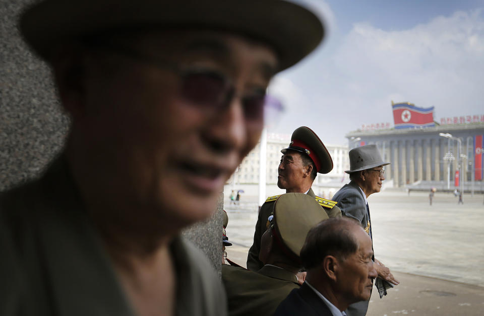 North Korean men wait for the start of a parade to celebrate the anniversary of the Korean War armistice agreement, Sunday, July 27, 2014, in Pyongyang, North Korea. North Koreans gathered at Kim Il Sung Square as part of celebrations for the 61st anniversary of the armistice that ended the Korean War.(AP Photo/Wong Maye-E)