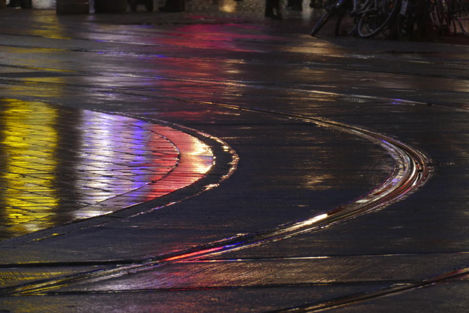 Regennasse Straße; Lichter; Straßenbahnschienen und bunte Wasserspiegelungen im Regen bei Abenddämmerung. (Bild aus Bremen: Getty Images)