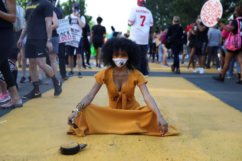 LaShawn Kenley, sentada en una parte del mensaje "Black Lives Matter" pintado en la calle frente a la Casa Blanca, mientras los manifestantes participan en una protesta contra la desigualdad racial tras la muerte en custodia policial de George Floyd en Mineápolis, en Washington