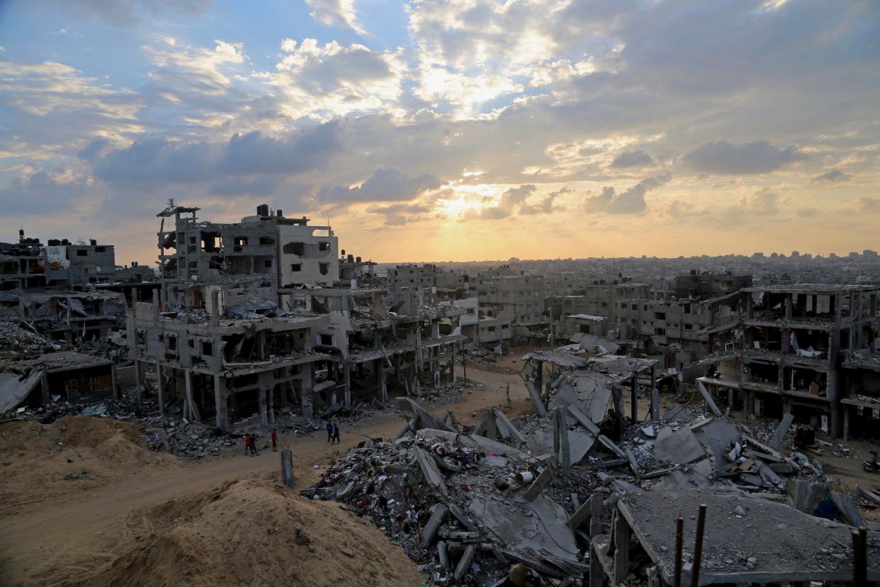 Palestinians walk between the rubble of a destroyed building in Shijaiyah neighborhood of Gaza City in the northern Gaza Strip.